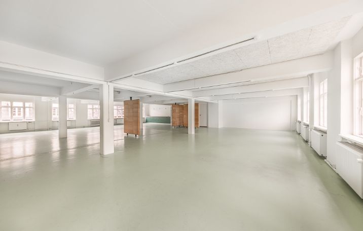 åbent kontormiljø med hvide vægge og grønne gulve  i kontor til leje på struenseegade 15 på nørrebro
