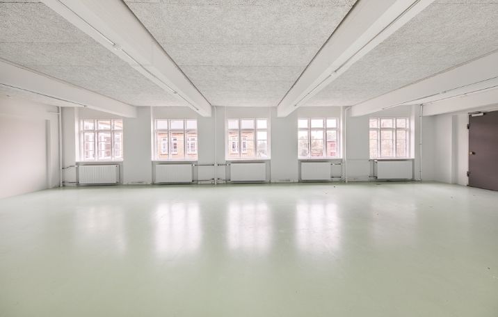 åbent kontormiljø med hvide vægge og grønne gulve og store sprossede fabriksvinduer i kontorlejemål på struenseegade 15 på nørrebro